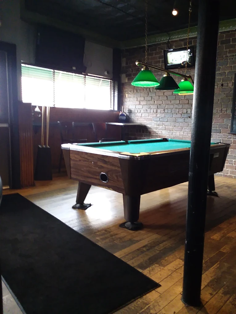 Duke's pool table room with exposed brick and green lamps